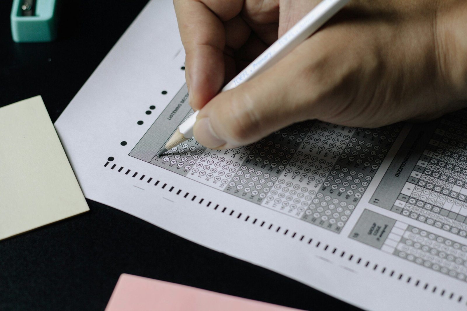 Persona rellenando una hoja de respuestas en un examen de opción múltiple.
